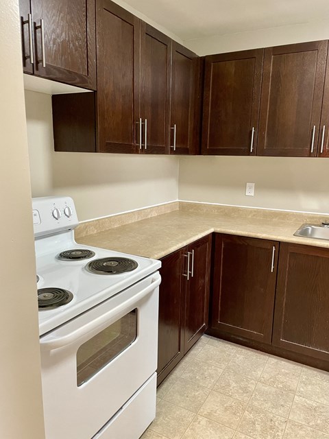 an empty kitchen with white appliances and wooden cabinets