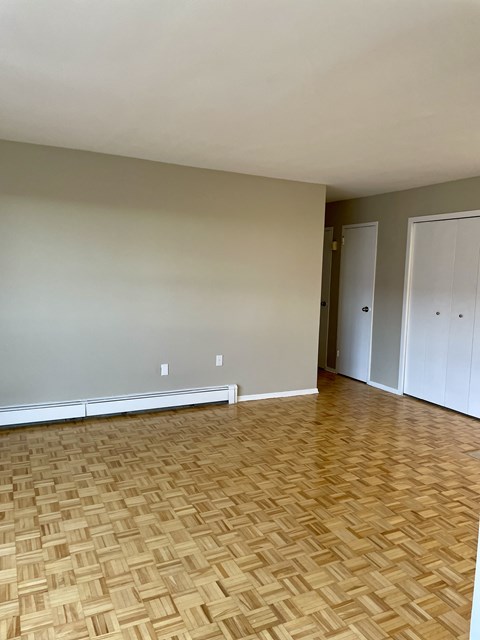 an empty living room with wood flooring and grey walls