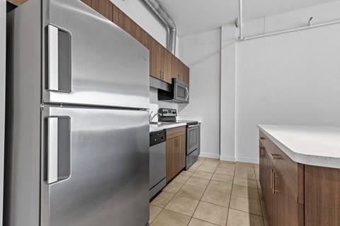 A stainless steel refrigerator is in a kitchen with wooden cabinets.