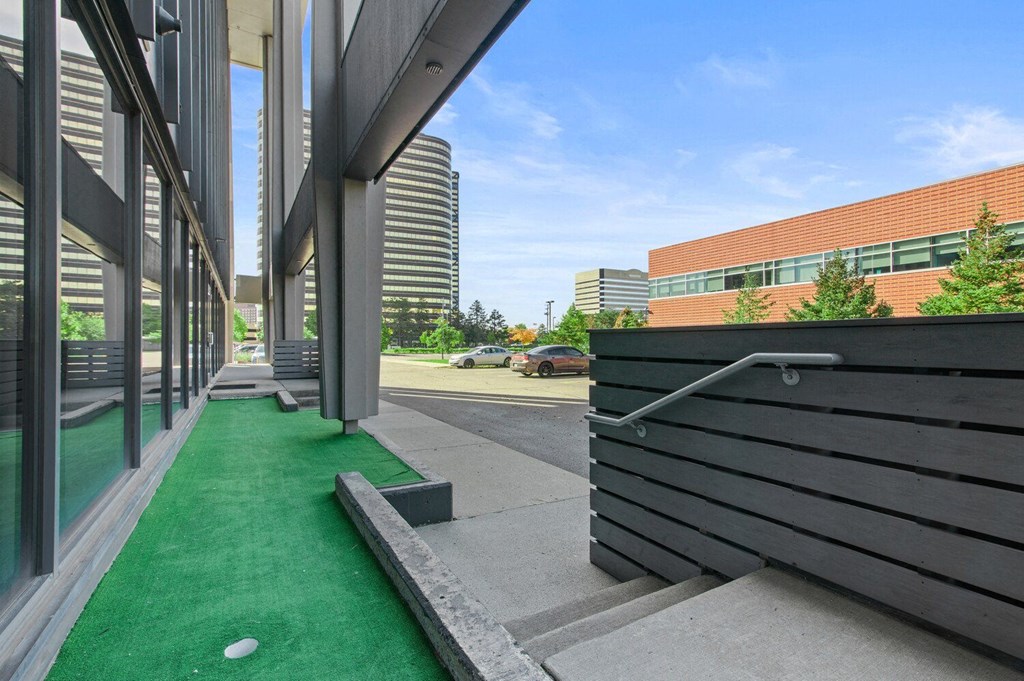 a green carpeted patio with a wooden bench next to a building