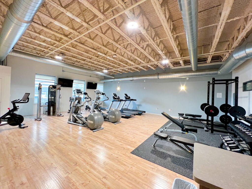 a gym with cardio equipment and weights on a wooden floor