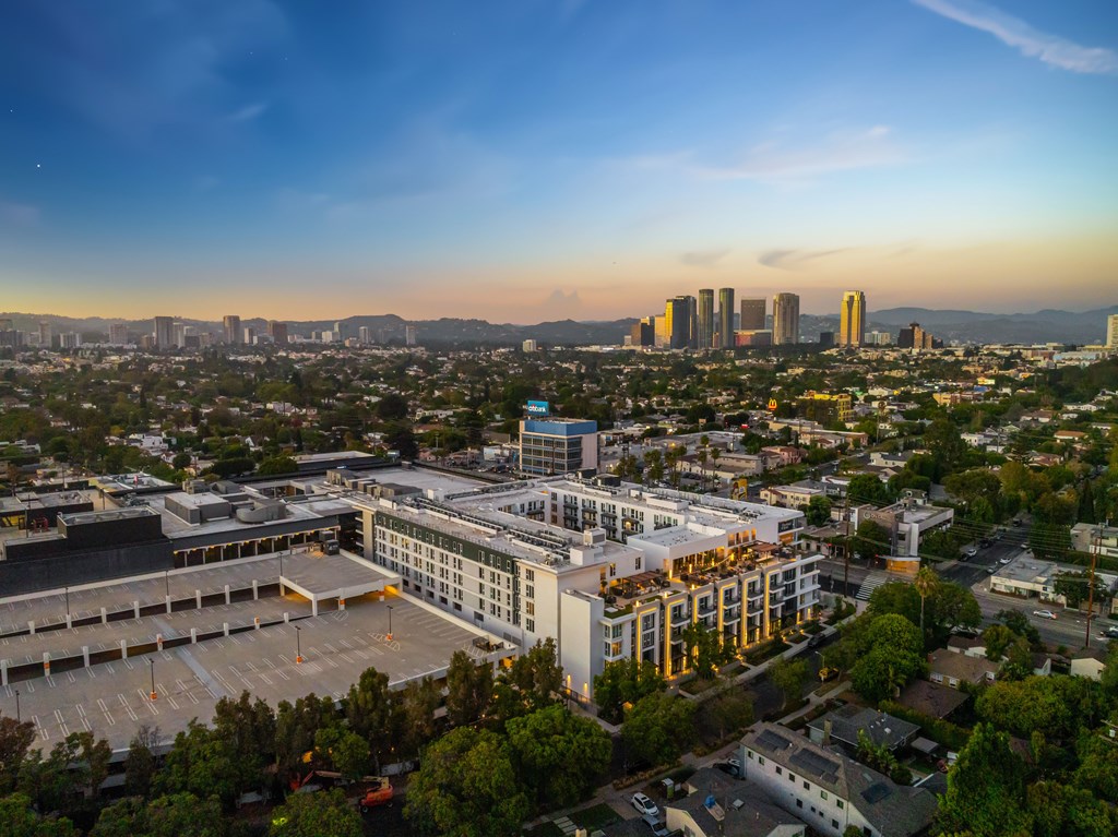 A cityscape with a large building in the foreground and mountains in the distance.