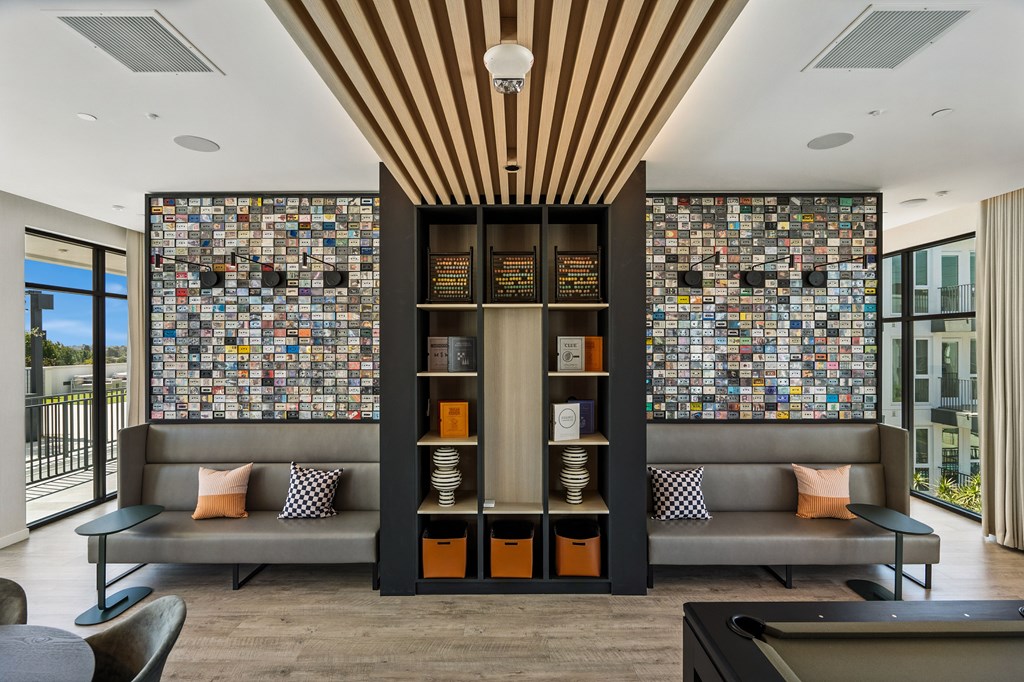 A modern living room with a grey sofa and a wall of tiles.