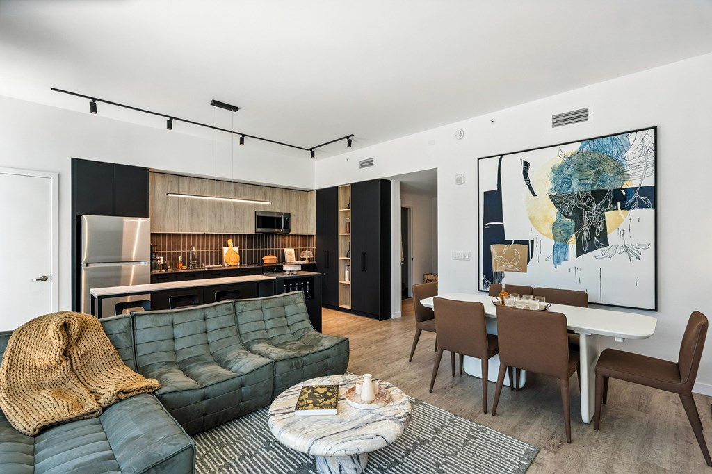 A modern living room with a green sofa and a dining table set up.