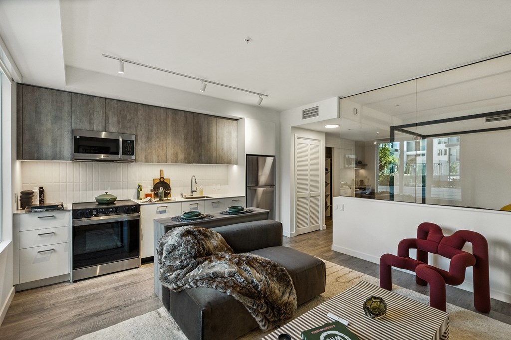 A modern kitchen with a black couch and a red chair.