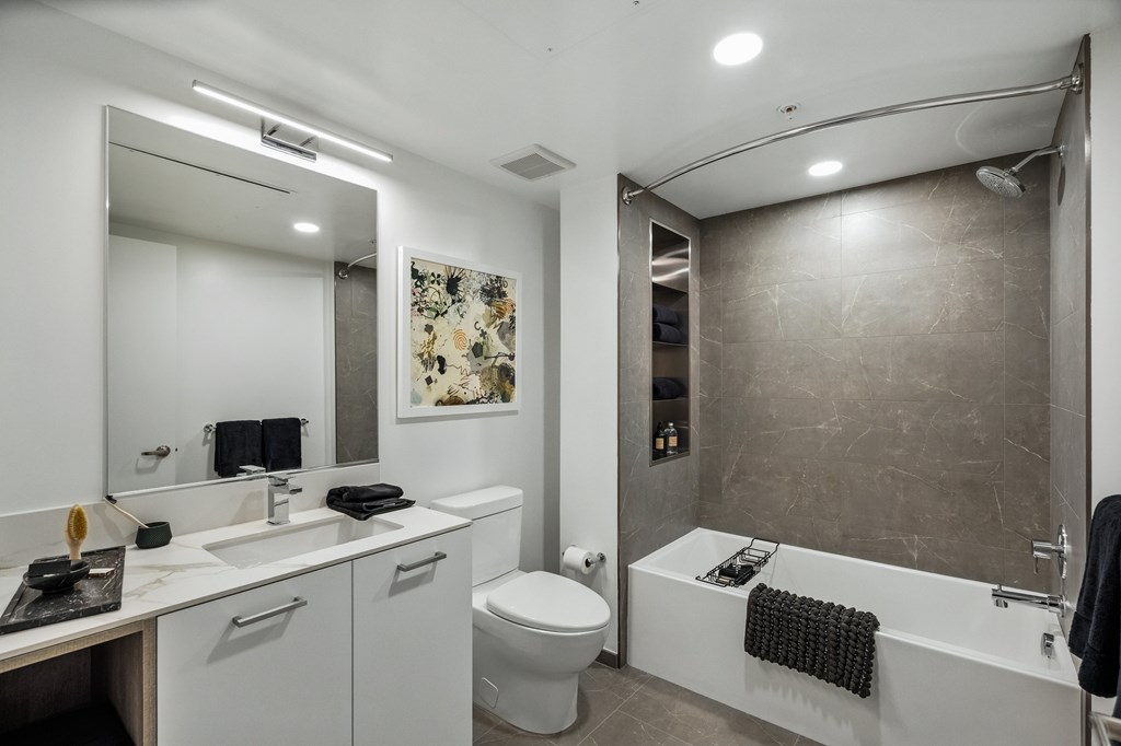 A modern bathroom with a white toilet, sink, and bathtub.