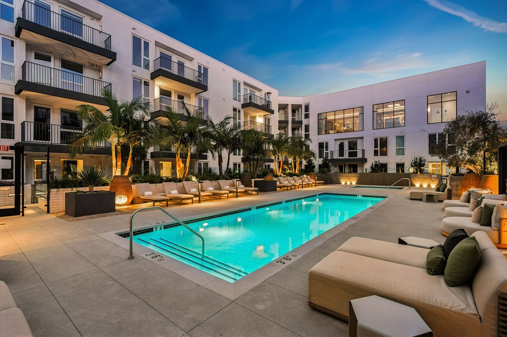 A swimming pool surrounded by lounge chairs and palm trees.