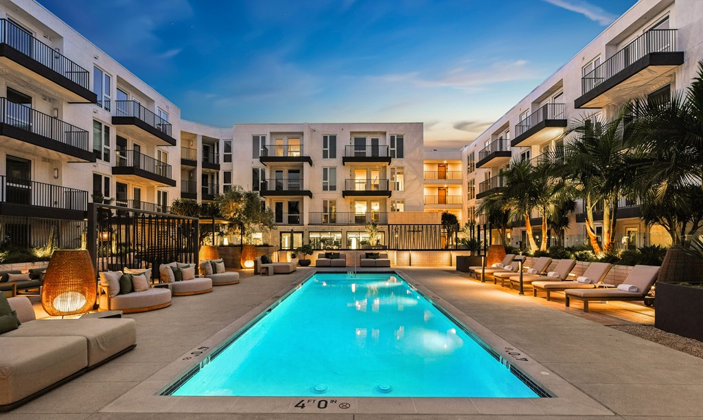 A large swimming pool surrounded by lounge chairs and palm trees.