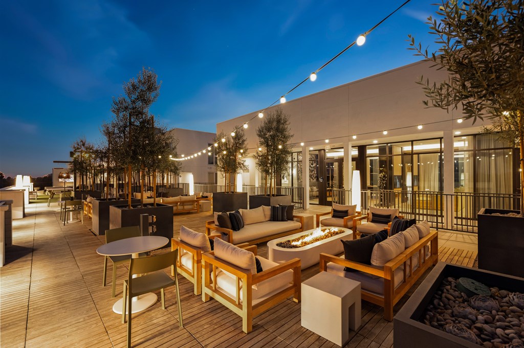 A patio with wooden furniture and string lights.