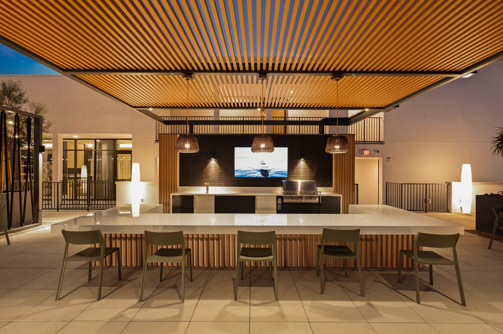 A modern outdoor dining area with a long table and chairs.