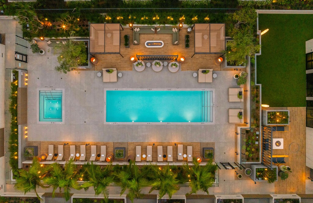 A pool surrounded by lounge chairs and greenery.