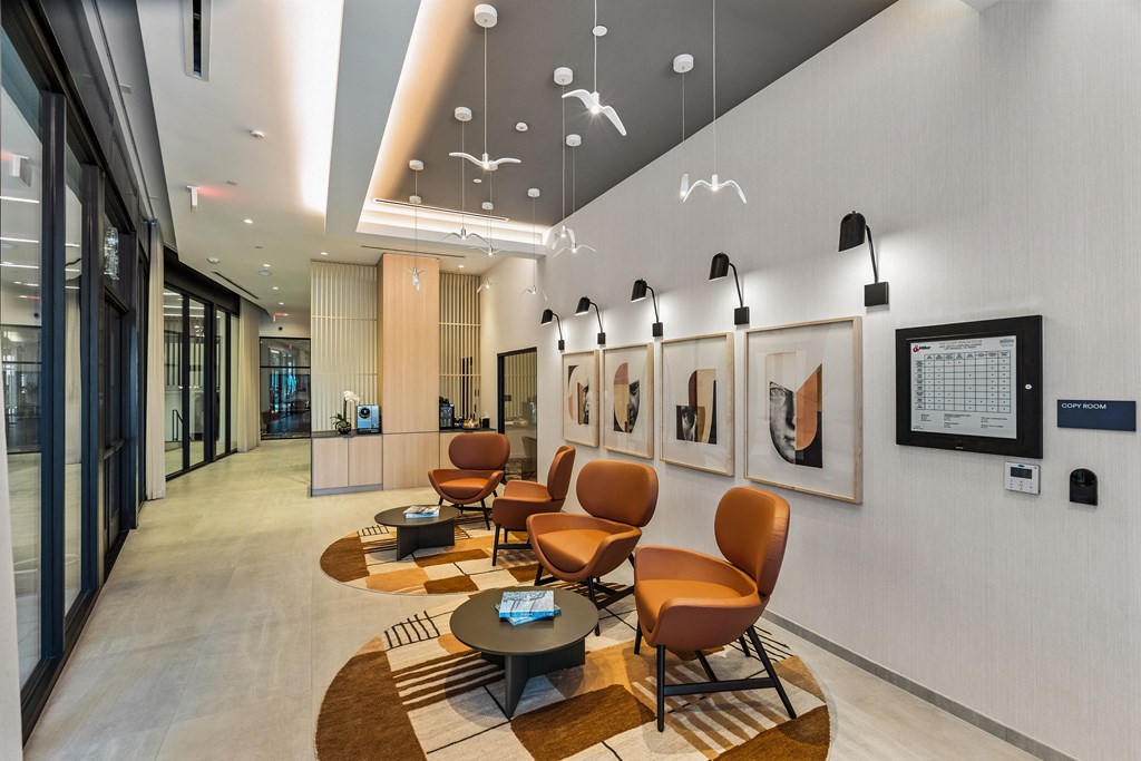 A modern waiting area with orange chairs and a wooden coffee table.