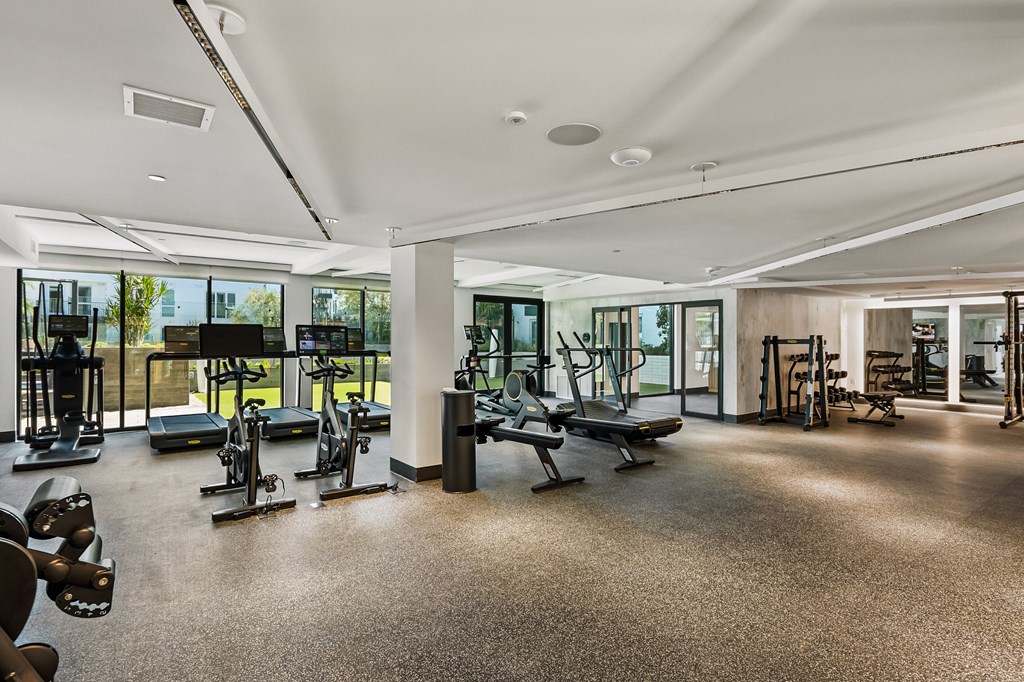 A spacious gym with a variety of equipment and a large mirror on the wall.