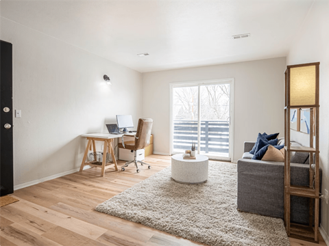 a living room with a couch and a desk and a window