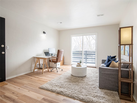 a living room with a couch and a desk and a window