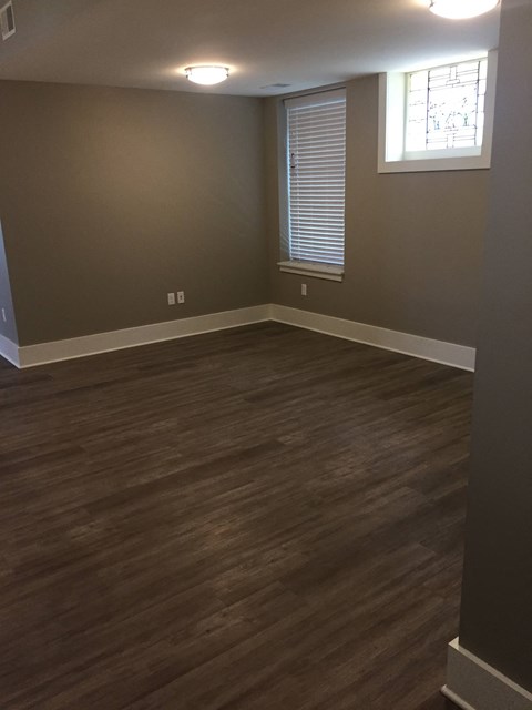 A room with wooden flooring and a window with blinds.