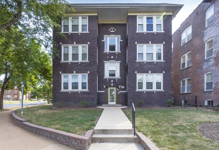 the front of a brick building with a sidewalk in front of it