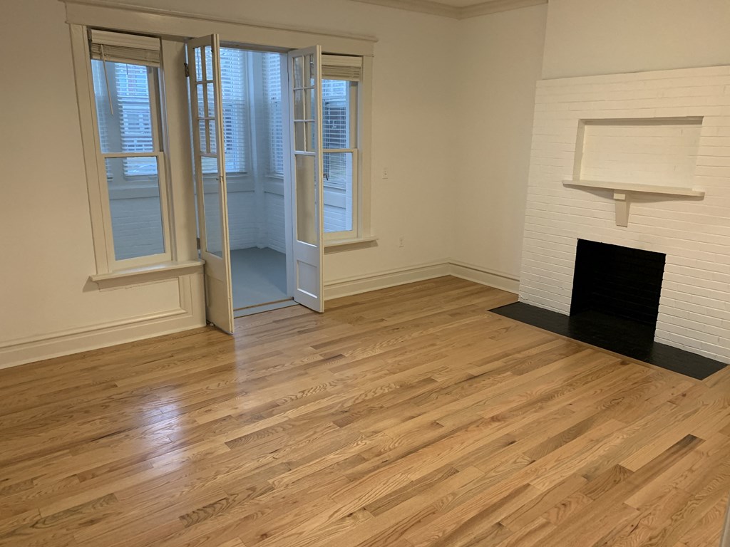 an empty living room with wood floors and a fireplace