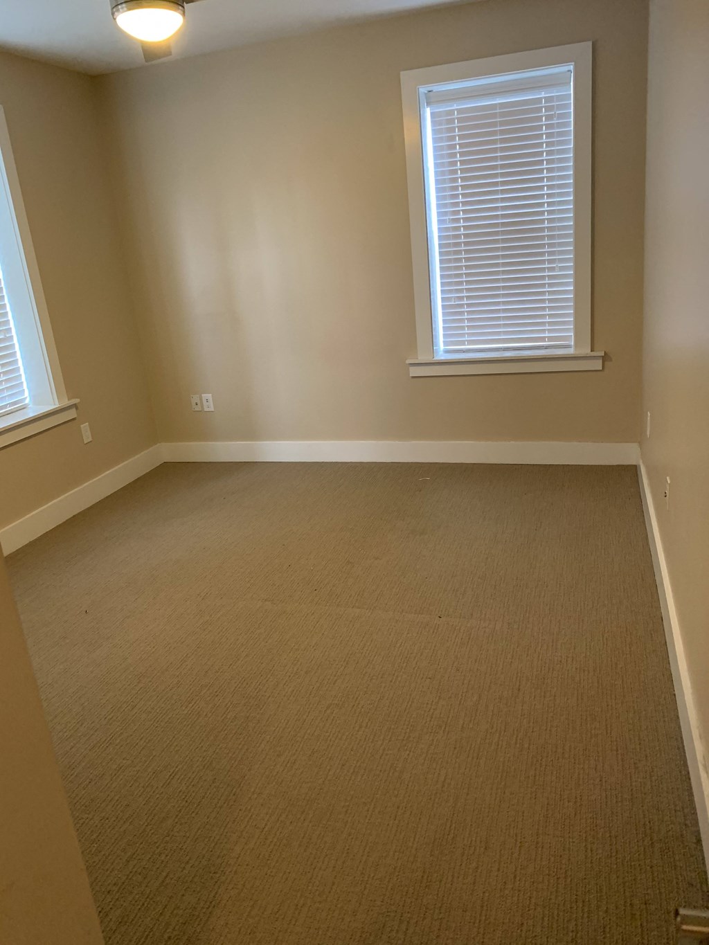 A room with a carpeted floor and a window with blinds.