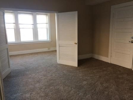 an empty room with a white door and a window