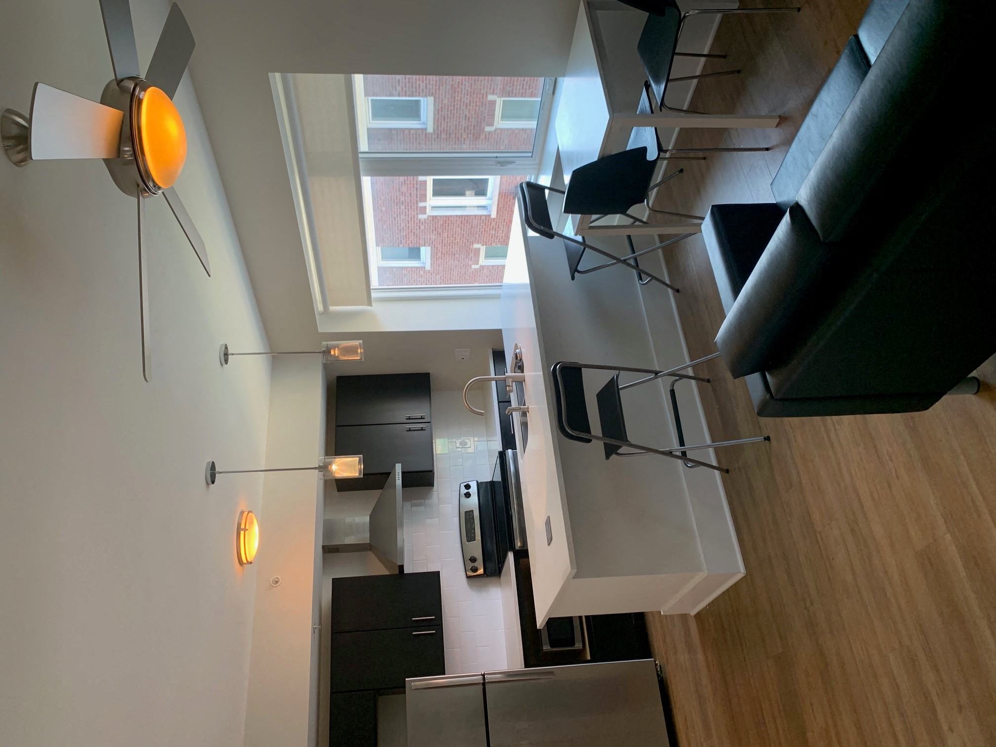 A modern kitchen with a fan and a view of a building outside.
