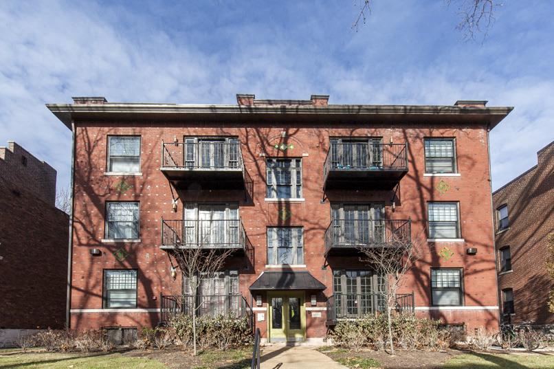 a red brick building with black windows and a sidewalk