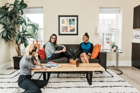 Three people are sitting on a couch in a living room.