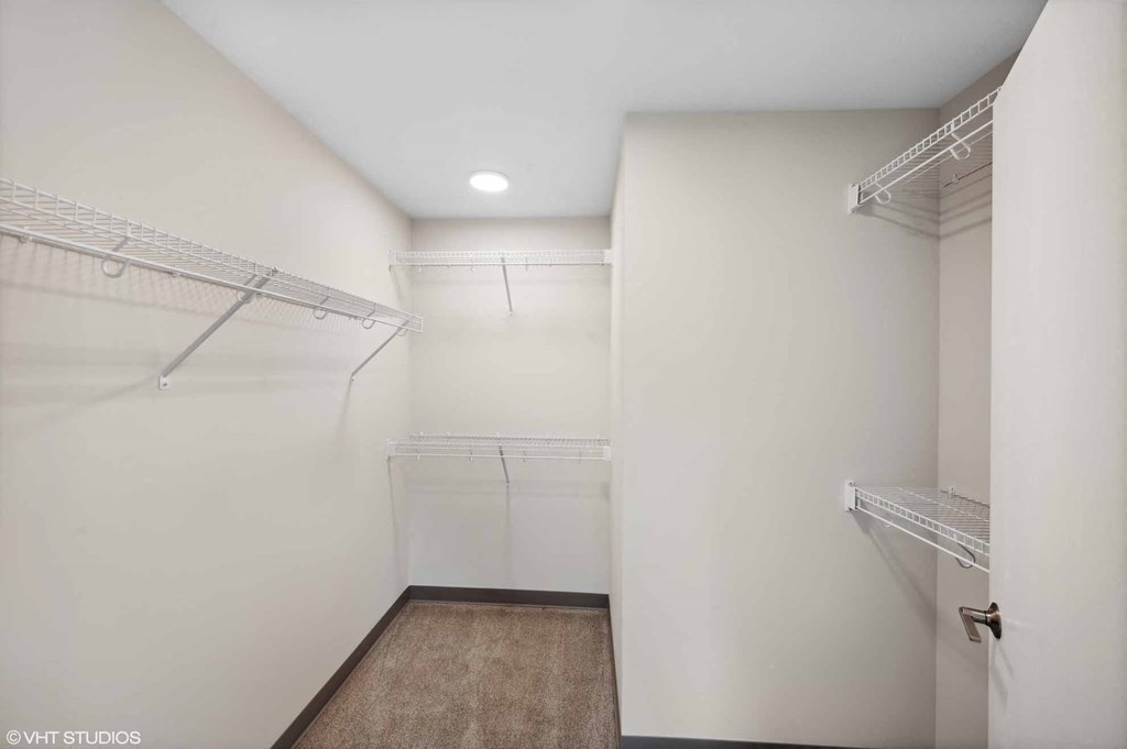 a walk in closet with white walls and shelves and racks