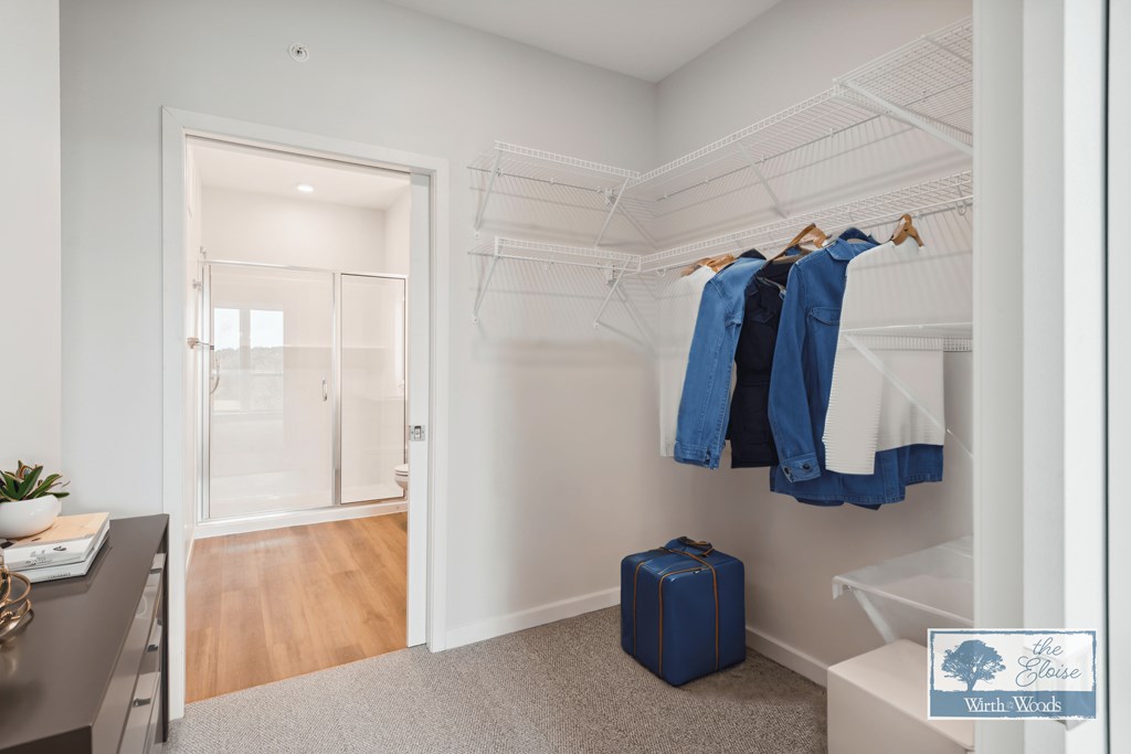 a walk in closet with a wardrobe and a blue suitcase