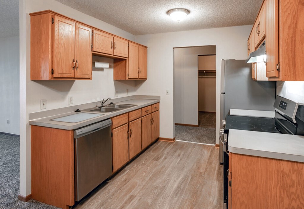 an empty kitchen with wooden cabinets and stainless steel appliances