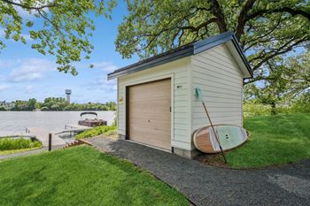 a small shed with a surfboard on the side of it next to a lake