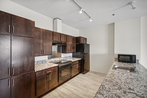 a kitchen with wooden cabinets and granite counter tops and a stainless steel stove and refrigerator