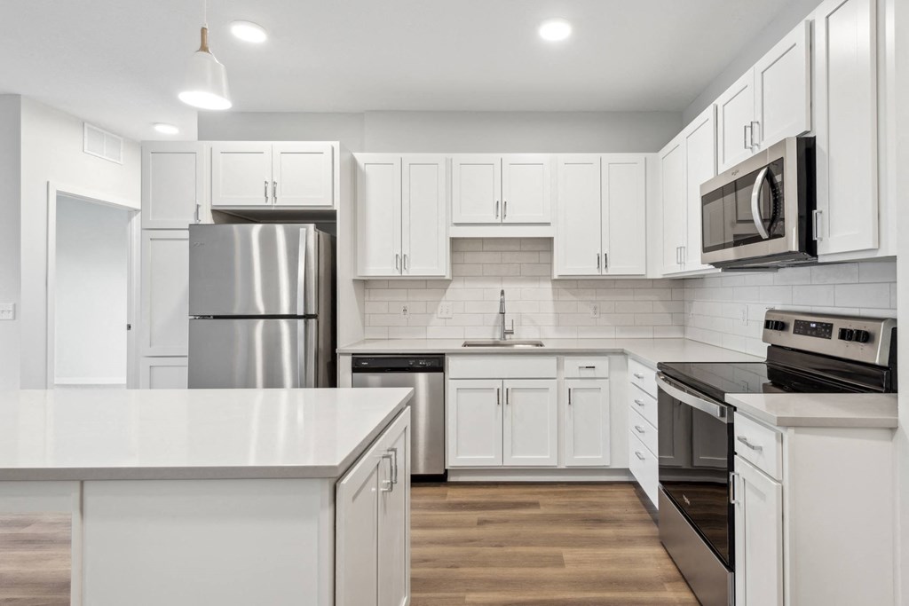 a white kitchen with stainless steel appliances and white cabinets