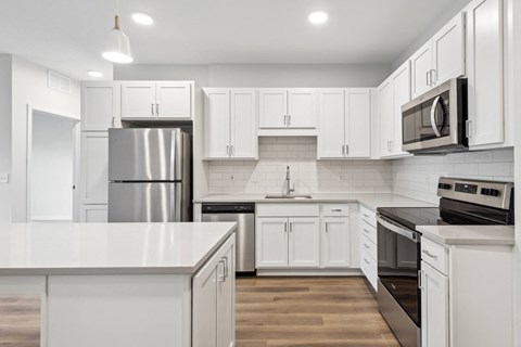 an all white kitchen with stainless steel appliances and white cabinets