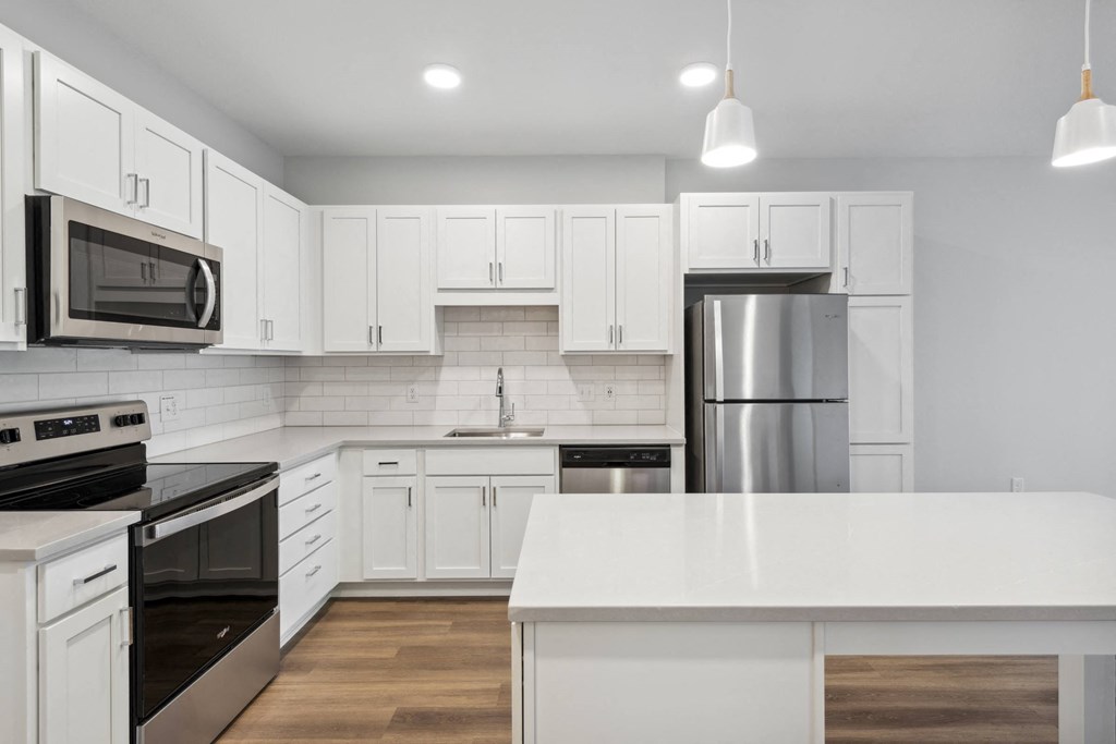 a white kitchen with stainless steel appliances and white cabinets