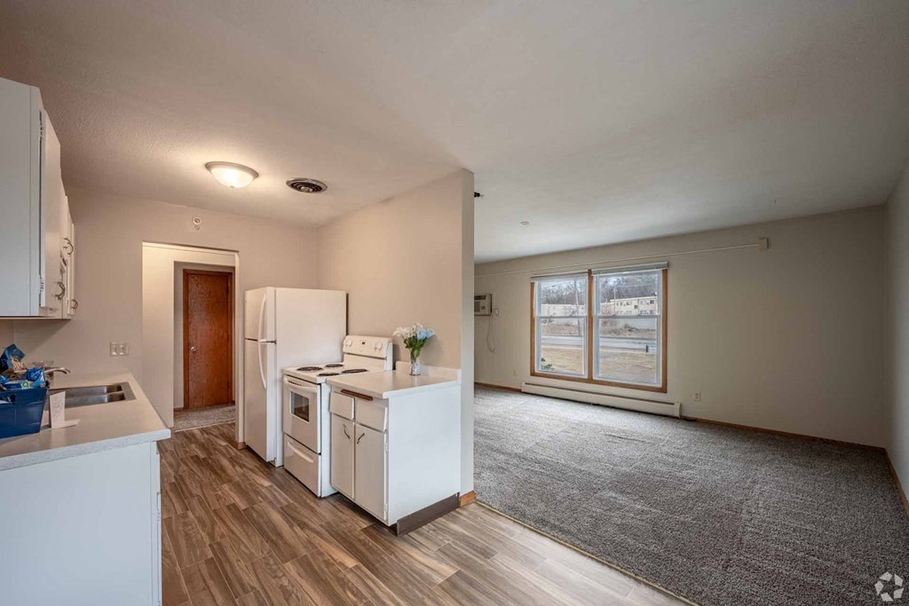 A kitchen with white appliances and a grey carpet.