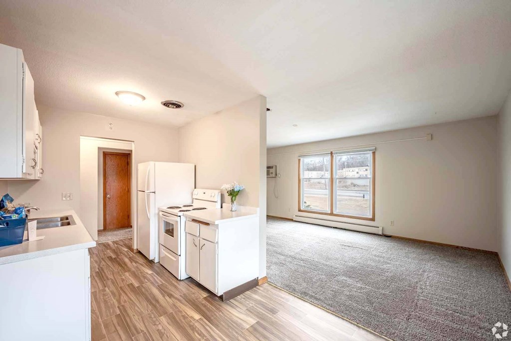 A kitchen with white appliances and a grey carpet.
