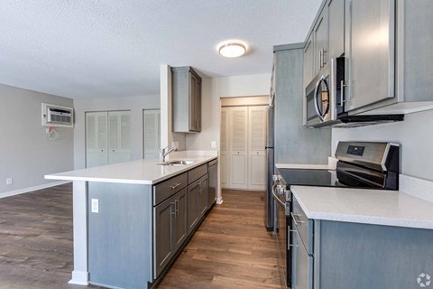 A kitchen with a white counter top and wooden floors.