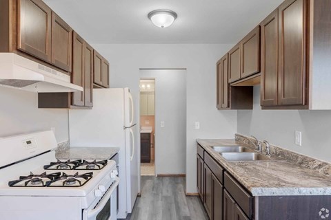 A kitchen with a white stove and a sink with a marble countertop.