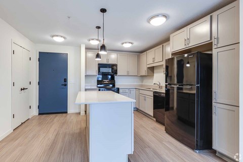 A kitchen with a black refrigerator and white countertops.