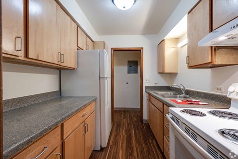 A kitchen with wooden cabinets and a white fridge.