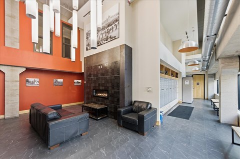 A living room with a black leather couch and a fireplace.