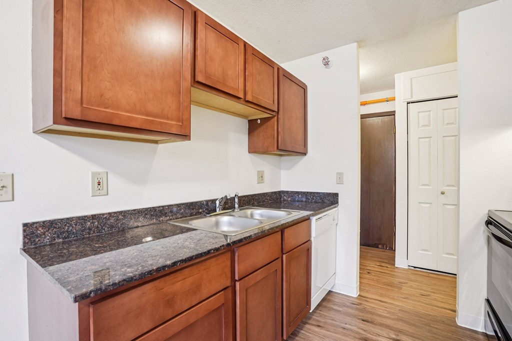 A kitchen with brown cabinets and a granite counter top.