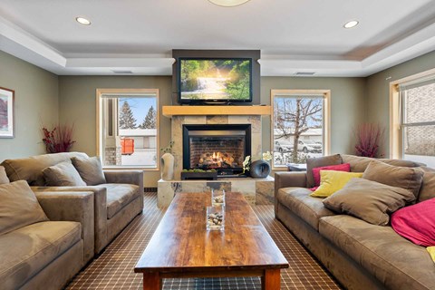 A living room with a fireplace and a television mounted above it.