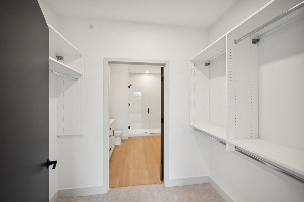 a walk in closet with white cabinets and a door to a bathroom