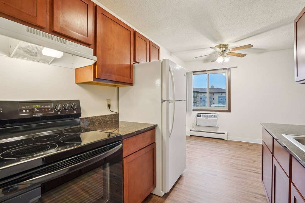 A kitchen with a black stove top oven and a white refrigerator.
