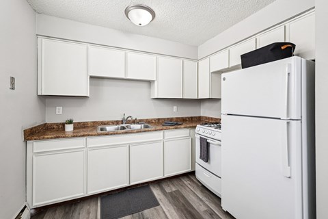 A white kitchen with a refrigerator on the right.