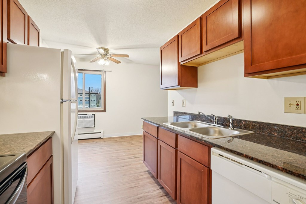 A kitchen with brown cabinets and a white fridge.