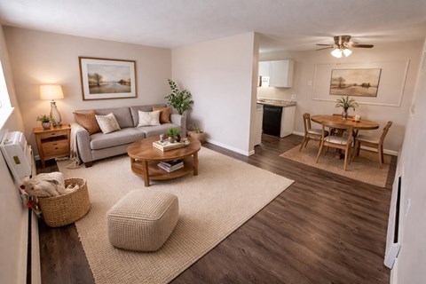 A living room with a couch, a chair, a table, and a potted plant.