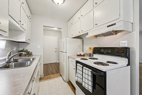 A white kitchen with a black stove top oven.